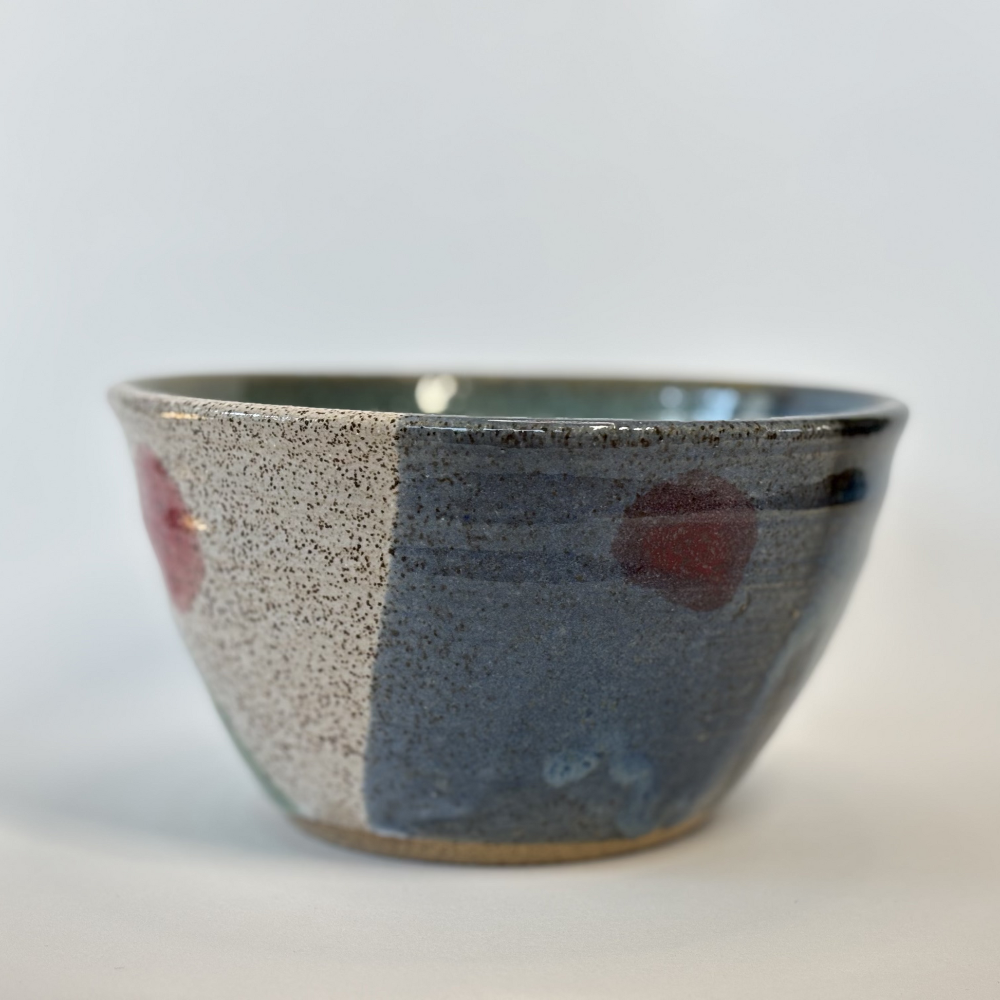 Ceramic bowl with speckled glaze on a white background