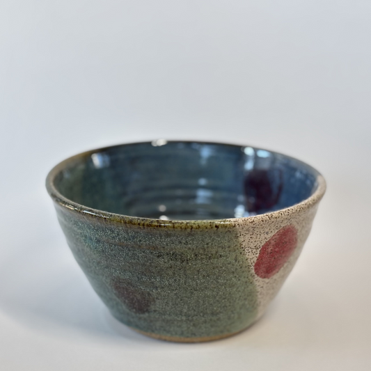 Ceramic bowl with speckled glaze and red accents on a white background